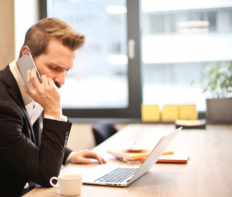 man-having-a-phone-call-in-front-of-a-laptop-8592642